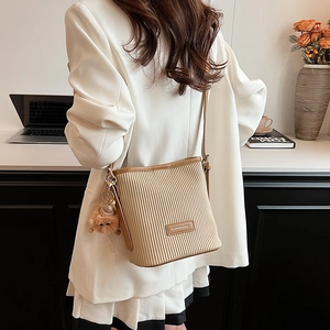Chic pleated bucket bag in beige with brown trim and cute plush monster pendant charm