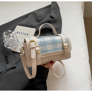 Detail showing the beige faux leather and blue plaid tweed stitching with gold buckles