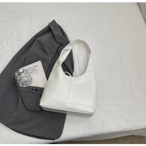 Top view of a minimalist white leather underarm bag on grey suit with decorative card