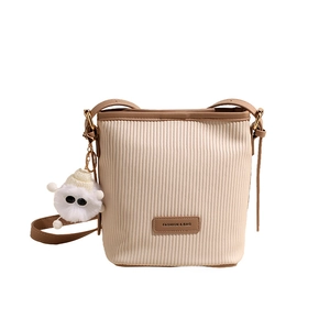 Chic pleated cream bucket bag with brown trim and cute plush monster charm accessory