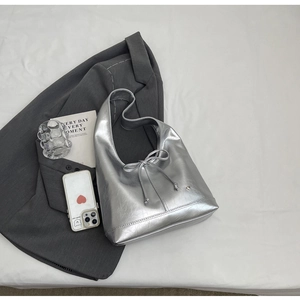 Detail of silver metallic hobo bag with drawstring bow and heart stud on gray suit
