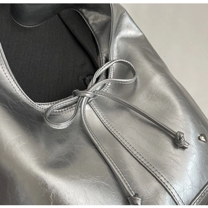 Detail of silver crinkled texture tote with bow tie and heart-shaped metal stud