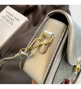 Detail showing the silver metallic leather texture and golden metal swivel hook on the bag