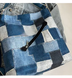 Detail of blue denim patchwork tote bag with wide strap and diagonal zipper pocket