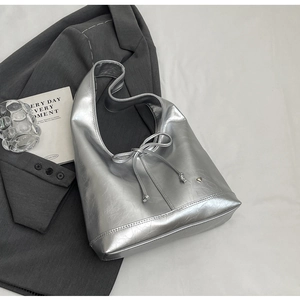 Detail of silver metallic hobo bag with ribbon bow and heart pendant on gray suit