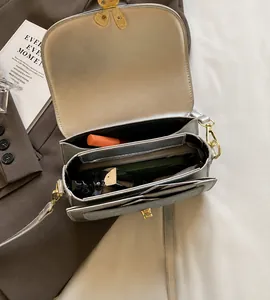 Detailed interior of denim saddle bag showing multi-layer compartments and gold bow buckle