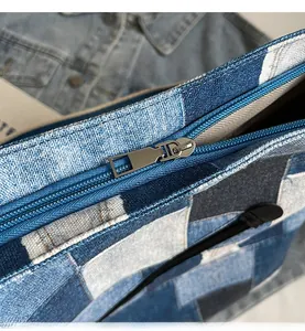 Detailed close-up of smooth silver metal zipper on a blue denim patchwork tote bag