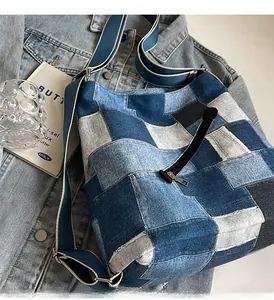 Close-up of patchwork denim tote with black zip pocket and wide blue shoulder strap
