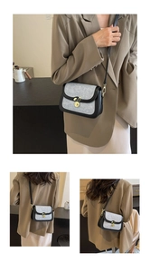 Close-up of denim saddle bag with golden bunny clasp and contrasting black leather trim