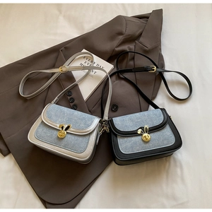 Detail of denim saddle bags with golden rabbit clasps on stylish brown blazer