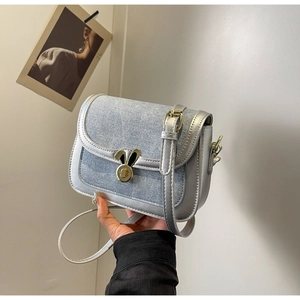 Detail of blue denim saddle bag with silver trim and golden rabbit ear metal buckle