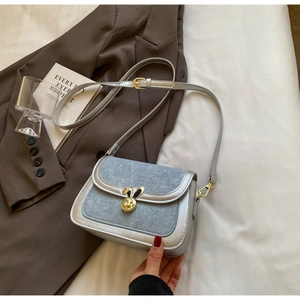 Macro detail of silver faux leather saddle bag with denim patchwork and rabbit ear lock