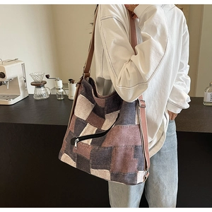 Detail view of a large canvas patchwork tote bag with side zipper on a model in a cafe