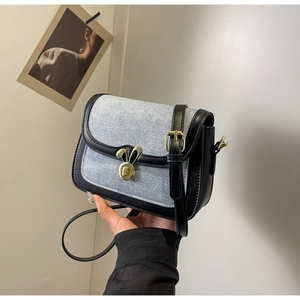 Detailed shot of denim saddle bag featuring a unique gold rabbit-shaped metal buckle