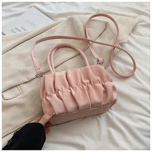Detail shot of the pink pleated cloud bag with a top handle and adjustable strap