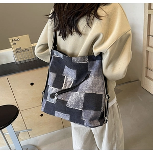 Detail of denim patchwork tote showing gray checkerboard pattern and diagonal zipper