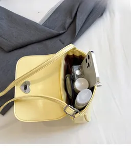 Detailed interior of the yellow crossbody bag showing capacity for phone and perfume