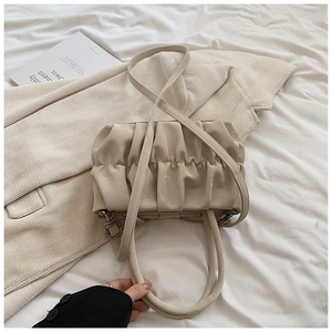 Detail of a creamy beige pleated cloud bag showing soft texture and dual strap design