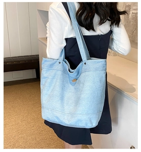 Rear view of a model wearing a light blue denim tote bag for daily commute use