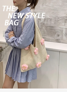 Détail d'un sac cabas en maille beige avec fleurs 3D roses porté à l'épaule