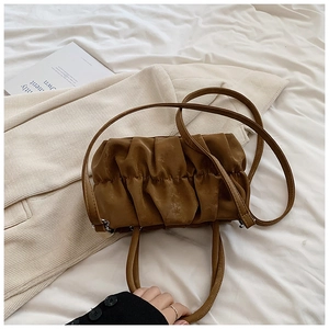 Detail of ruched leather texture on a brown cloud bag with slim shoulder strap