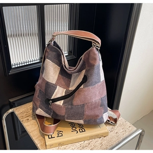 Detail of multi-color patchwork denim tote bag with wide strap and side zipper