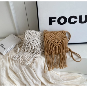 Detail of bohemian straw crossbody bags with intricate weaving and long fringe tassels