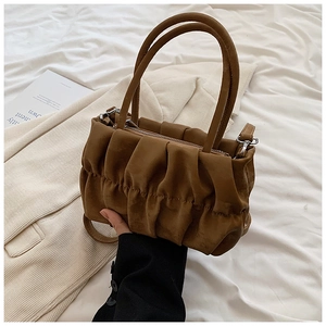 Detail of a dark brown pleated cloud bag with slim handles on a neutral background