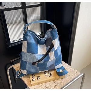 Detail of multi-tone denim patchwork tote with wide adjustable strap and metal zipper