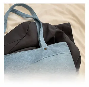 Close-up of durable stitched handle and leather patch on blue denim tote bag