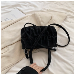 Detail of black pleated cloud bag in matte faux leather with silver metal buckle and strap