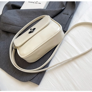 Detail view of cream PU leather crossbody bag featuring silver twist-lock and smooth texture