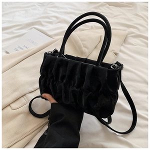 Detail of black pleated cloud bag showing velvet texture and silver metal zipper closure
