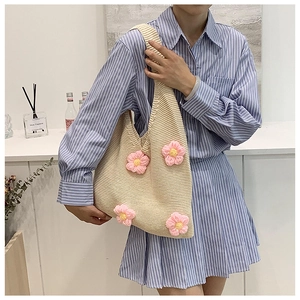 Détails de la maille d'un sac crème avec des fleurs roses au crochet faites à la main