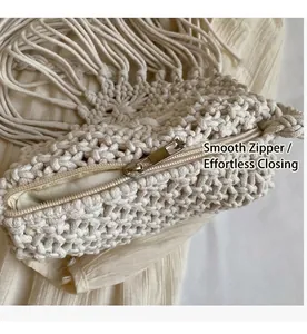 Detail of a beige woven straw bag with smooth metal zipper closure and tassel fringe
