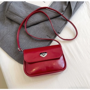 Detail of red glossy leather crossbody bag with a silver heart-shaped metal twist lock