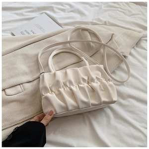Detailed view of the creamy white pleated cloud bag with elegant leather texture and strap