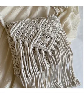 Close-up of bohemian woven straw bag with handmade tassel detail and cotton rope texture