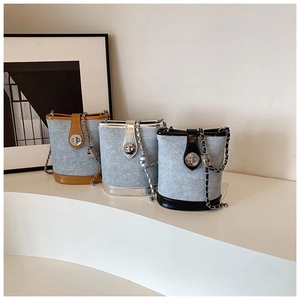 Close-up of stylish denim bucket bags with metallic chains and silver turn-lock buckles