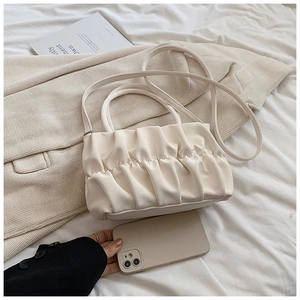 Detailed view of cream pleated cloud bag showing soft faux leather texture and top handle