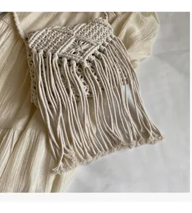 Detail of bohemian macrame straw bag featuring geometric weaving and long tassels