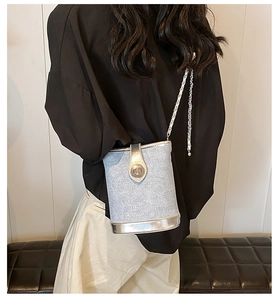 Detail of light blue denim bucket bag with silver mirror trim and metal chain strap