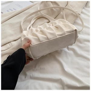 Detail shot of beige ruched cloud bag showing vertical pleats and soft faux leather texture