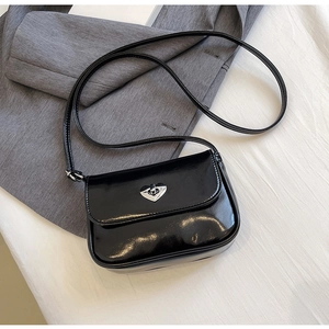 Detail of glossy black patent leather bag with a silver heart-shaped metal twist lock