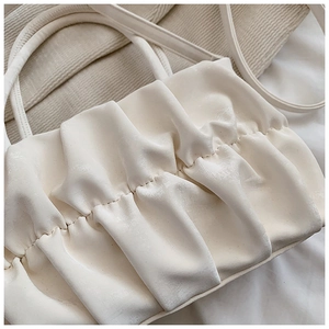 Close-up of white pleated leather texture and fine stitching on the minimalist cloud bag