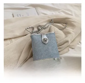 Detailed shot of light blue denim and silver leather bucket bag with chain strap