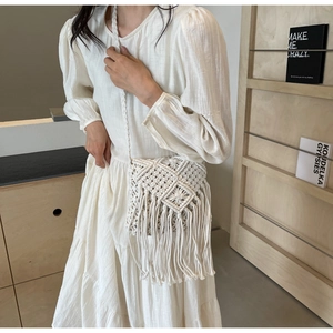 Detail of bohemian white woven straw bag featuring intricate mesh and long fringe