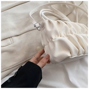 Detailed view of the off-white ruched texture and soft leather-like material of the bag