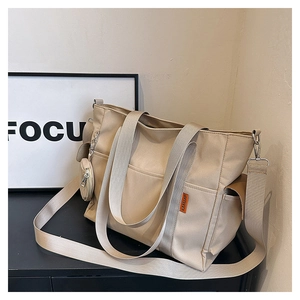 Detail of beige nylon tote bag with small round coin purse and adjustable shoulder strap