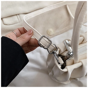 Close-up of cream pleated cloud bag showing silver zipper and soft micro-velvet texture
